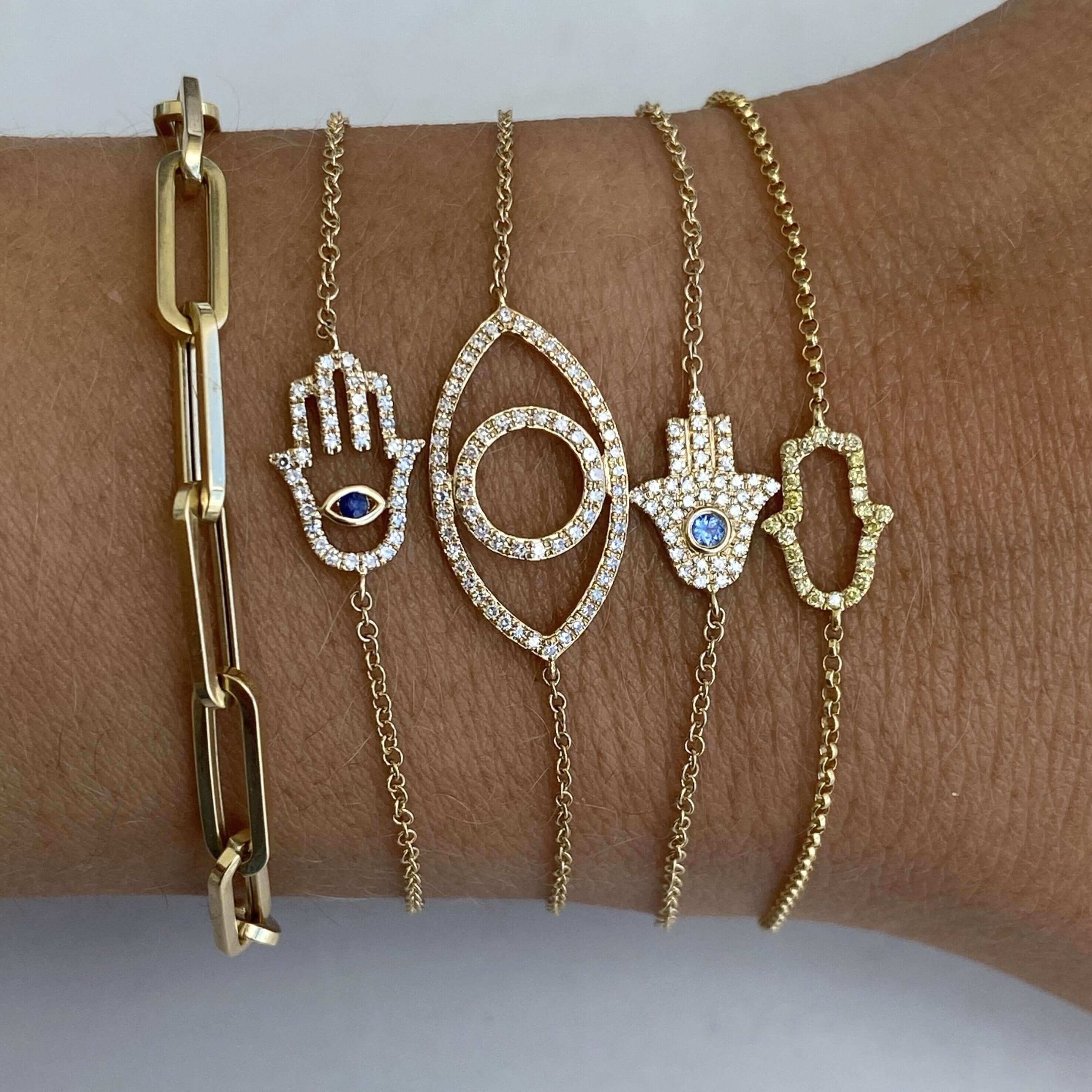 Elegant gold and diamond bracelets featuring hamsa and evil eye designs showcased on wrist, exquisite jewelry from our premium collection