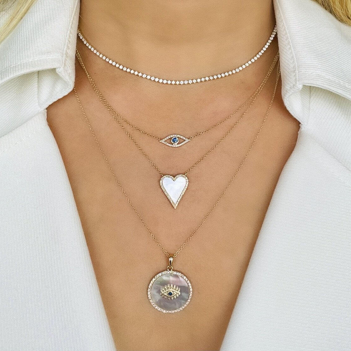 Pave Diamond Evil Eye Necklace layered with heart and circular pendants on a model's neck