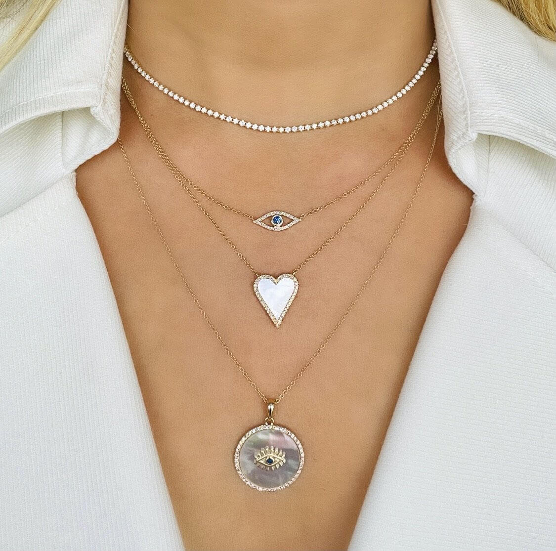 Woman wearing layered necklaces with eye, heart, and pendant designs from our premium jewelry collection