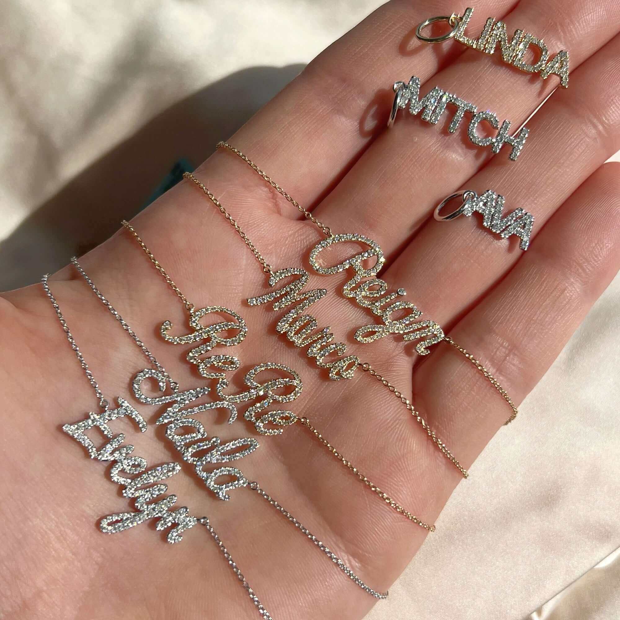 Hand showcasing personalized name necklaces and rings from our jewelry brand, featuring elegant script designs on a neutral background.