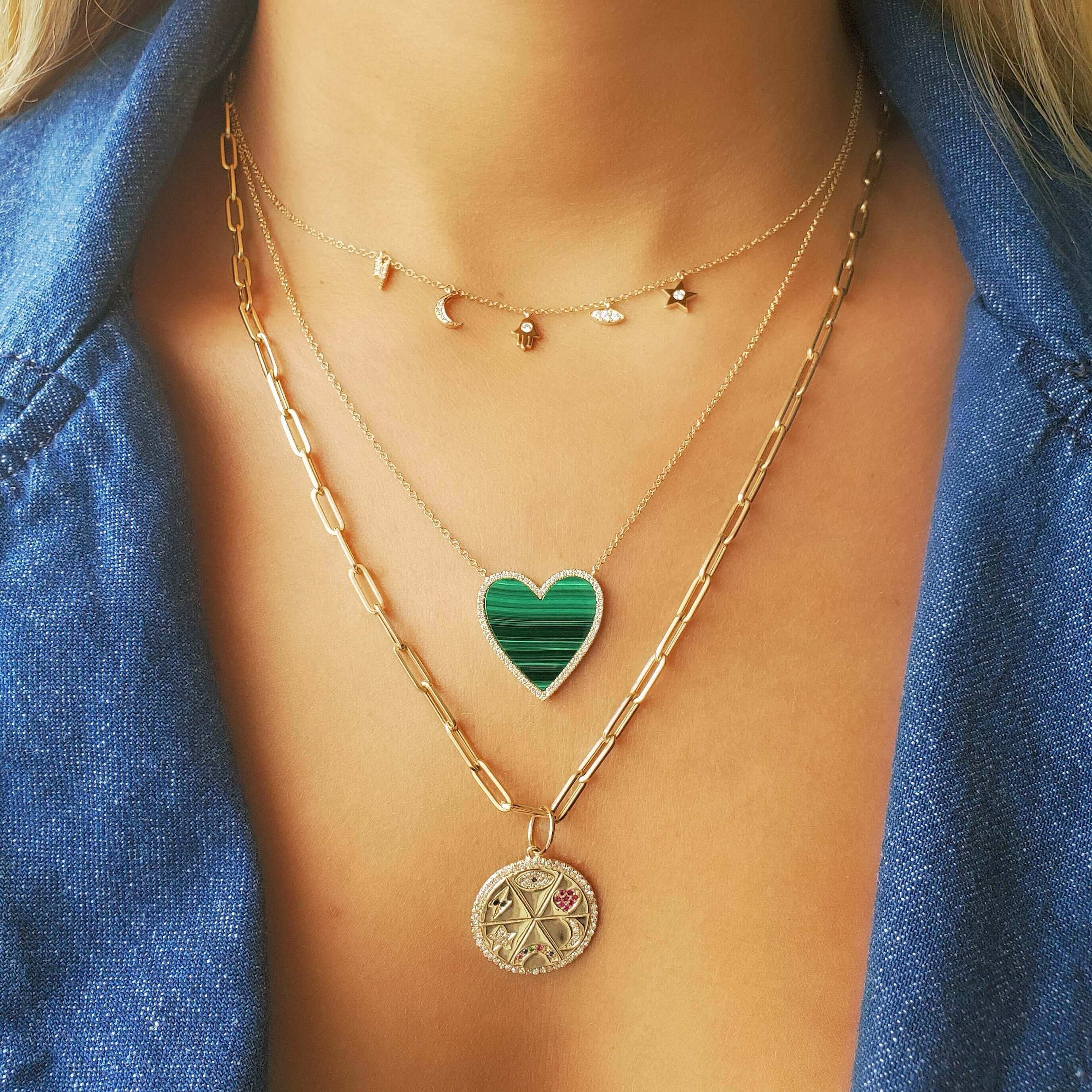 Woman wearing layered necklaces in gold with a crescent moon, star, and heart pendant by our luxury jewelry brand.