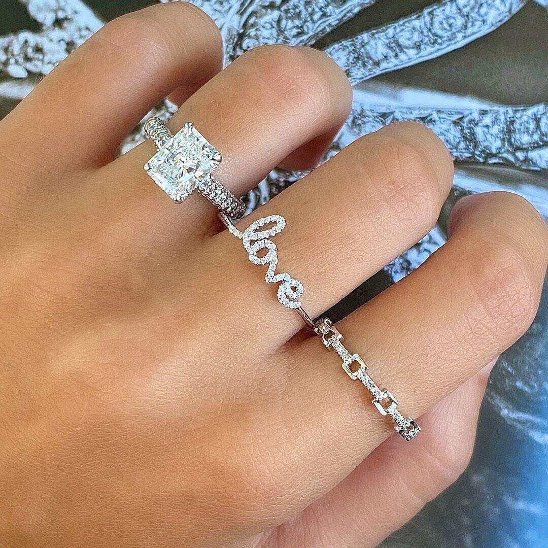 Elegant diamond engagement ring and "love" bracelet on hand, showcasing our premium jewelry brand collection.