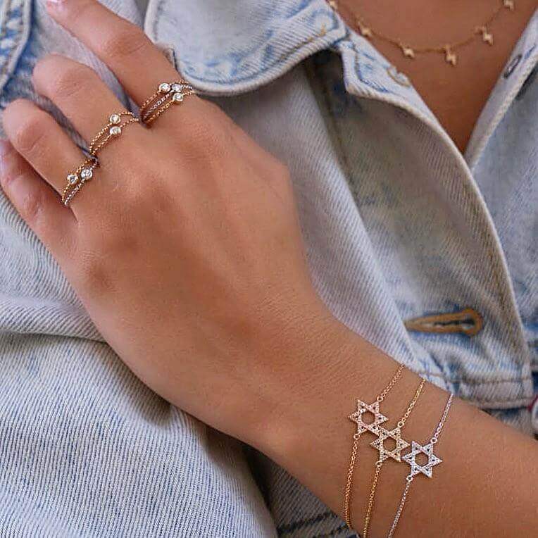 Woman wearing delicate star bracelets and gemstone rings from our jewelry collection
