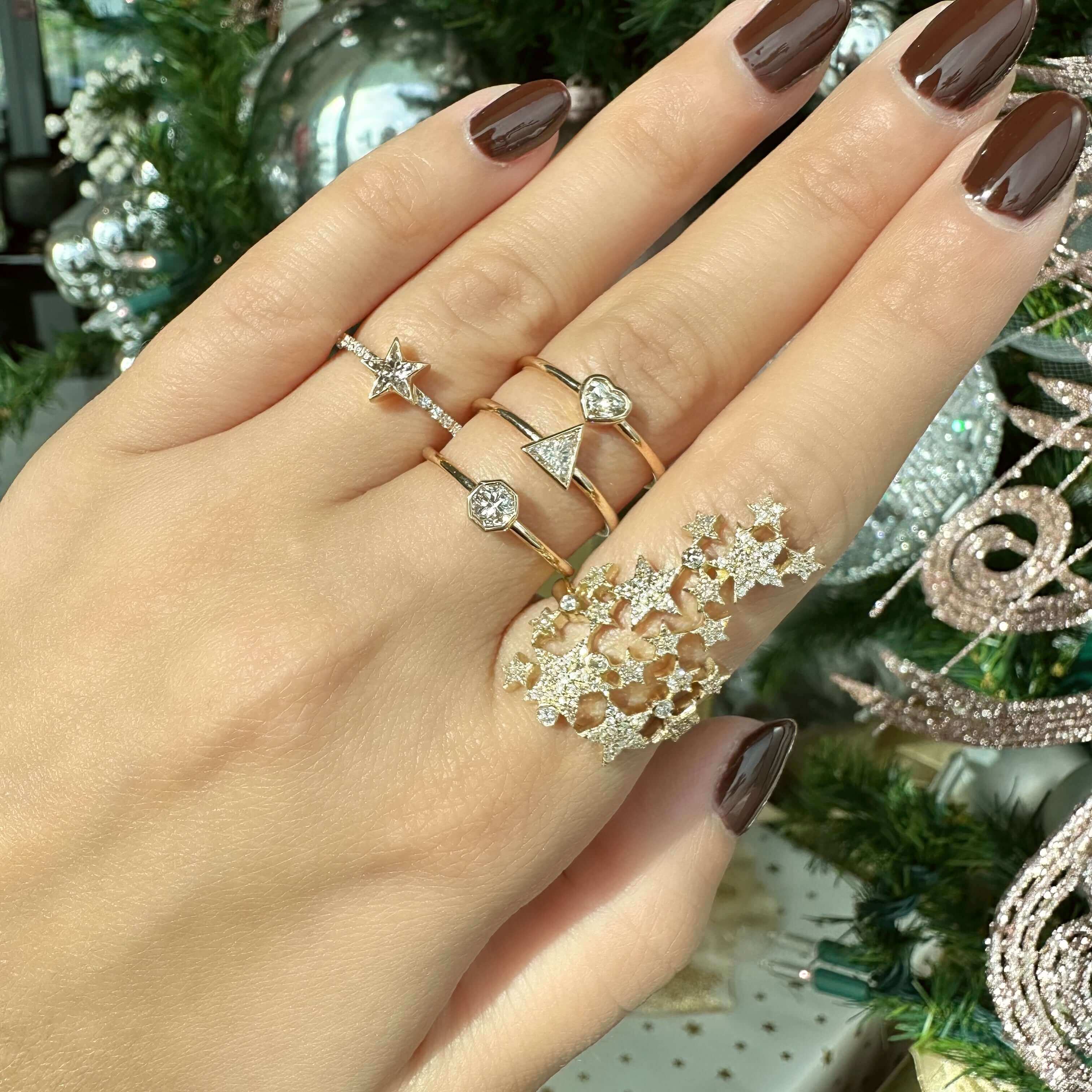 Hand adorned with stylish gold rings featuring stars, hearts, and geometric designs from our exclusive jewelry collection