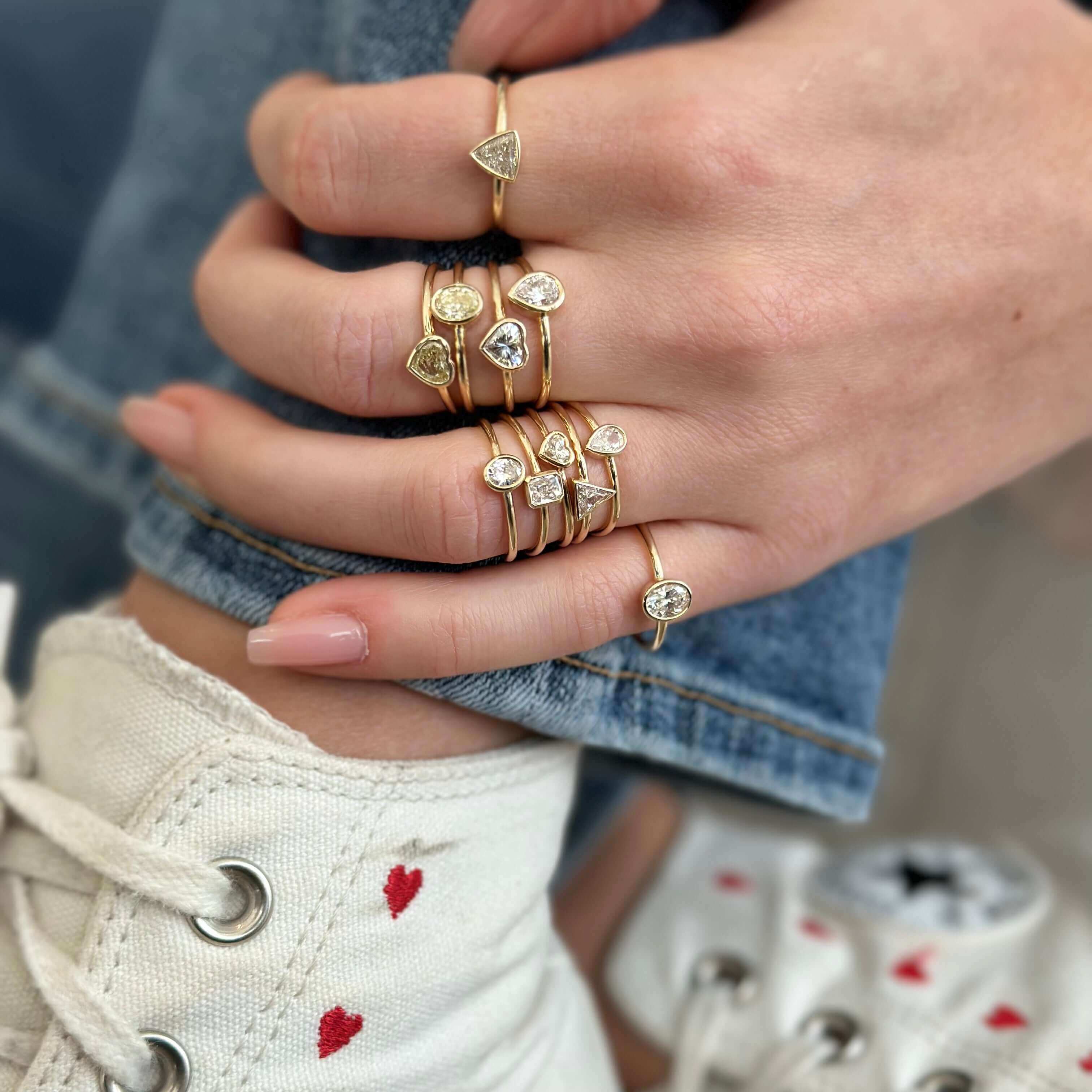 Petite Oval Diamond Bezel Ring shown among delicate gold rings on a hand, highlighting Izakov Fine Jewelry's elegant design.