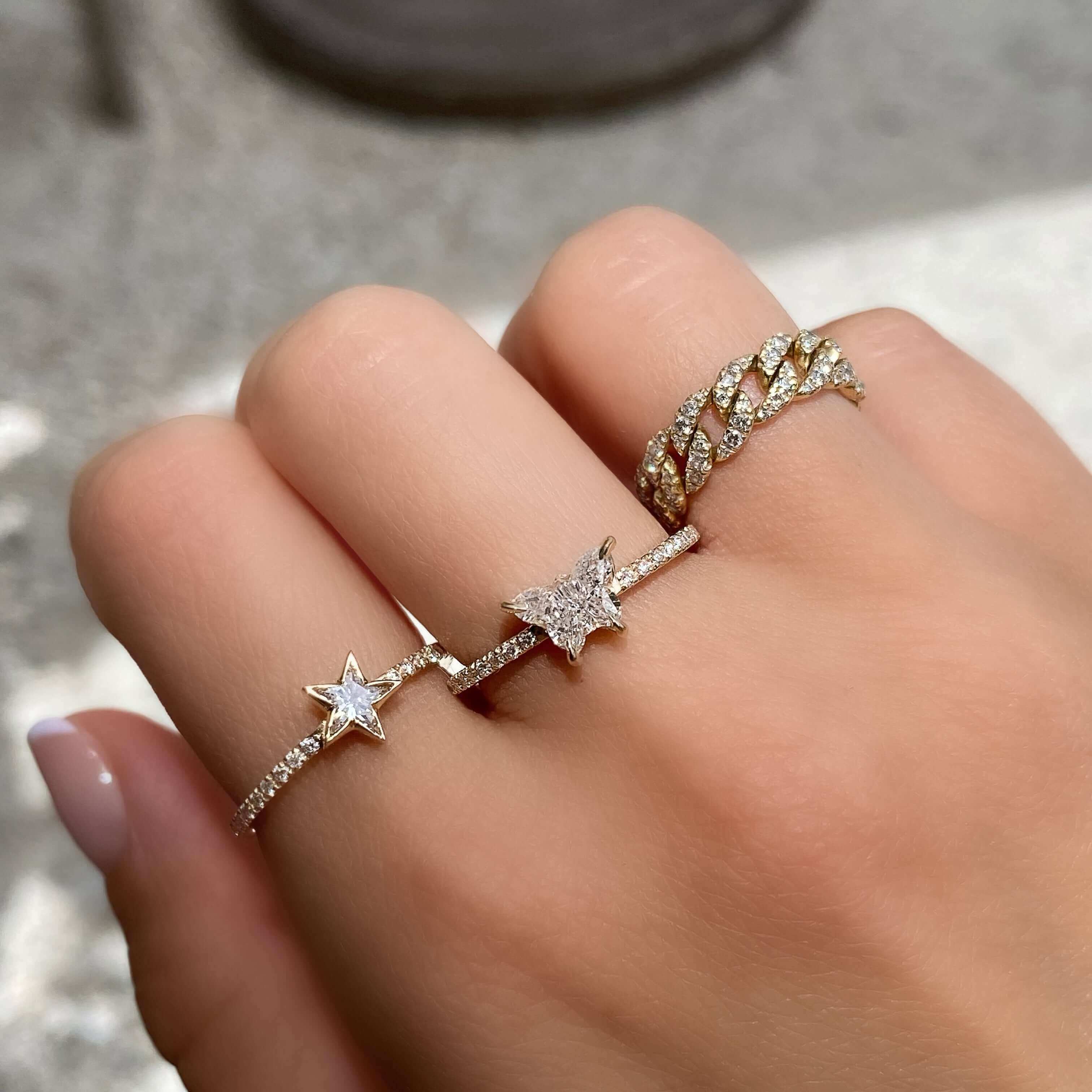 Woman's hand wearing three stunning gold rings with diamond accents from our exclusive jewelry collection.