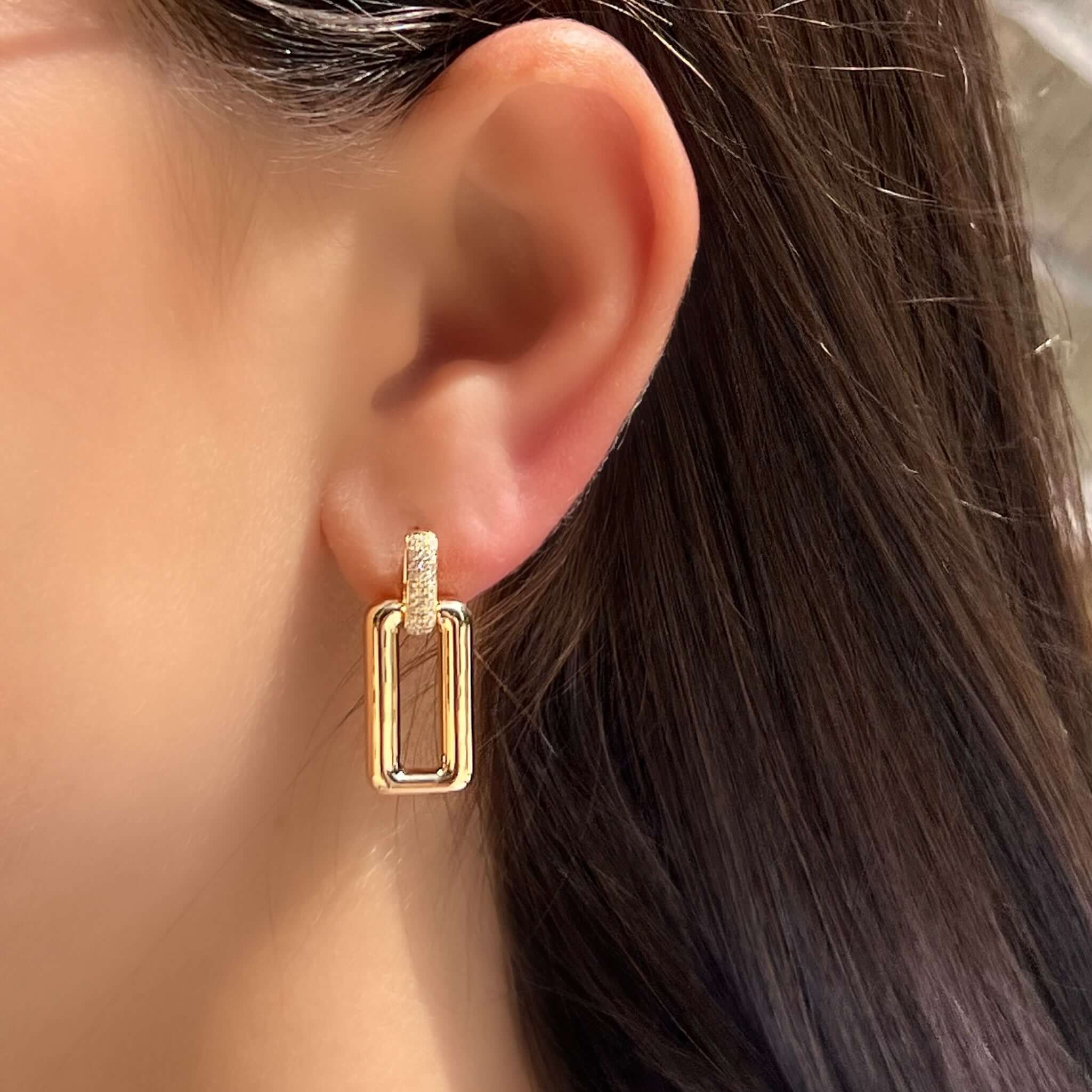 Stylish gold drop earrings featuring a unique geometric design, worn on a model's ear.
