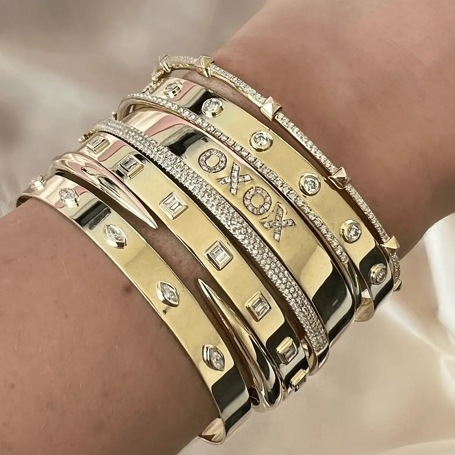 A collection of stylish gold bangle bracelets adorned with diamonds and unique designs on a wrist.