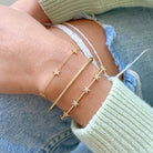 Micro Pave Diamond Stars Bangle worn with two other star bracelets, showcasing 14k gold designs.