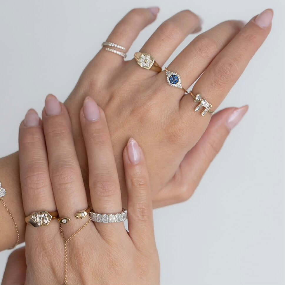Elegant display of multiple rings including a Hebrew Chai Baguette Diamond Ring set in 14k gold, showcasing fine jewelry.
