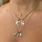 Woman wearing layered gold necklaces with initial pendants and figurine charms from our elegant jewelry collection