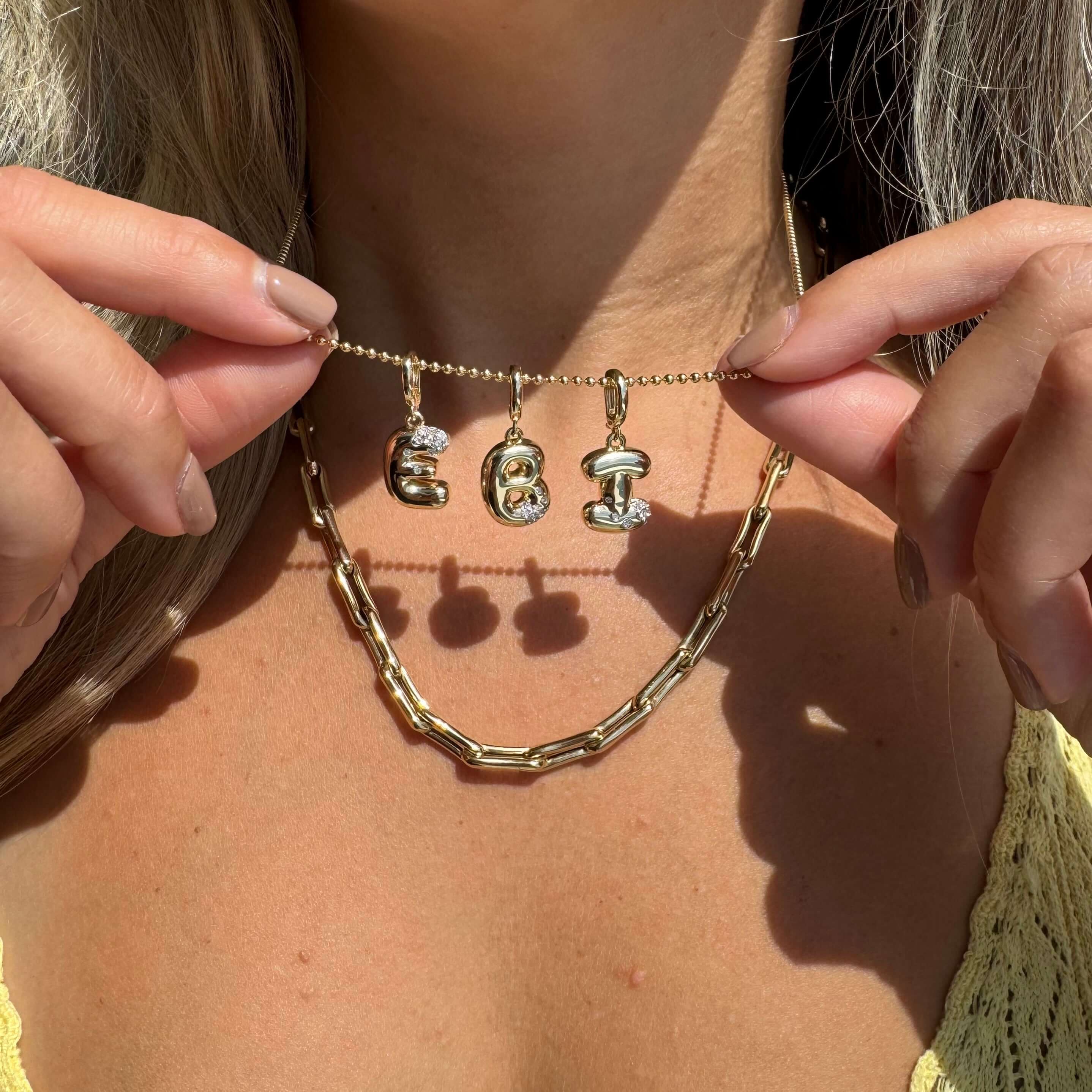14K Gold Bubble Letter Diamond Necklace Charm with diamond accents on a woman