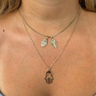 Woman wearing gold necklaces with Hamsa pendants showcasing our jewelry brand's intricate designs.