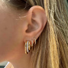 Woman wearing elegant gold and diamond hoop earrings from our jewelry collection.