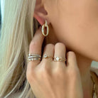 Woman wearing stacked rings and gold hoop earring from our jewelry brand