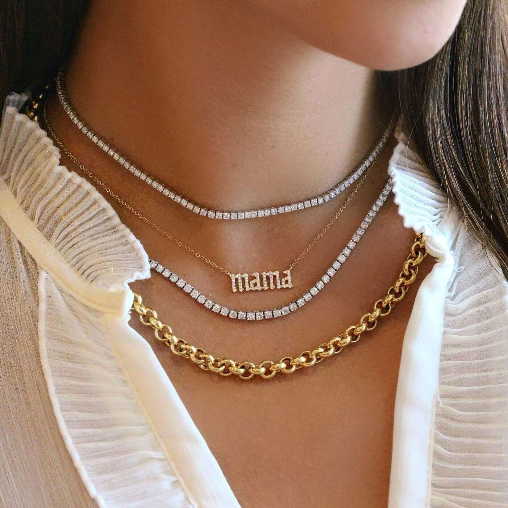 Woman wearing layered gold necklaces, including a "mama" pendant and chain, showcasing our elegant jewelry collection.