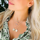 Woman wearing layered necklaces with zodiac pendants and ear cuff from our jewelry collection