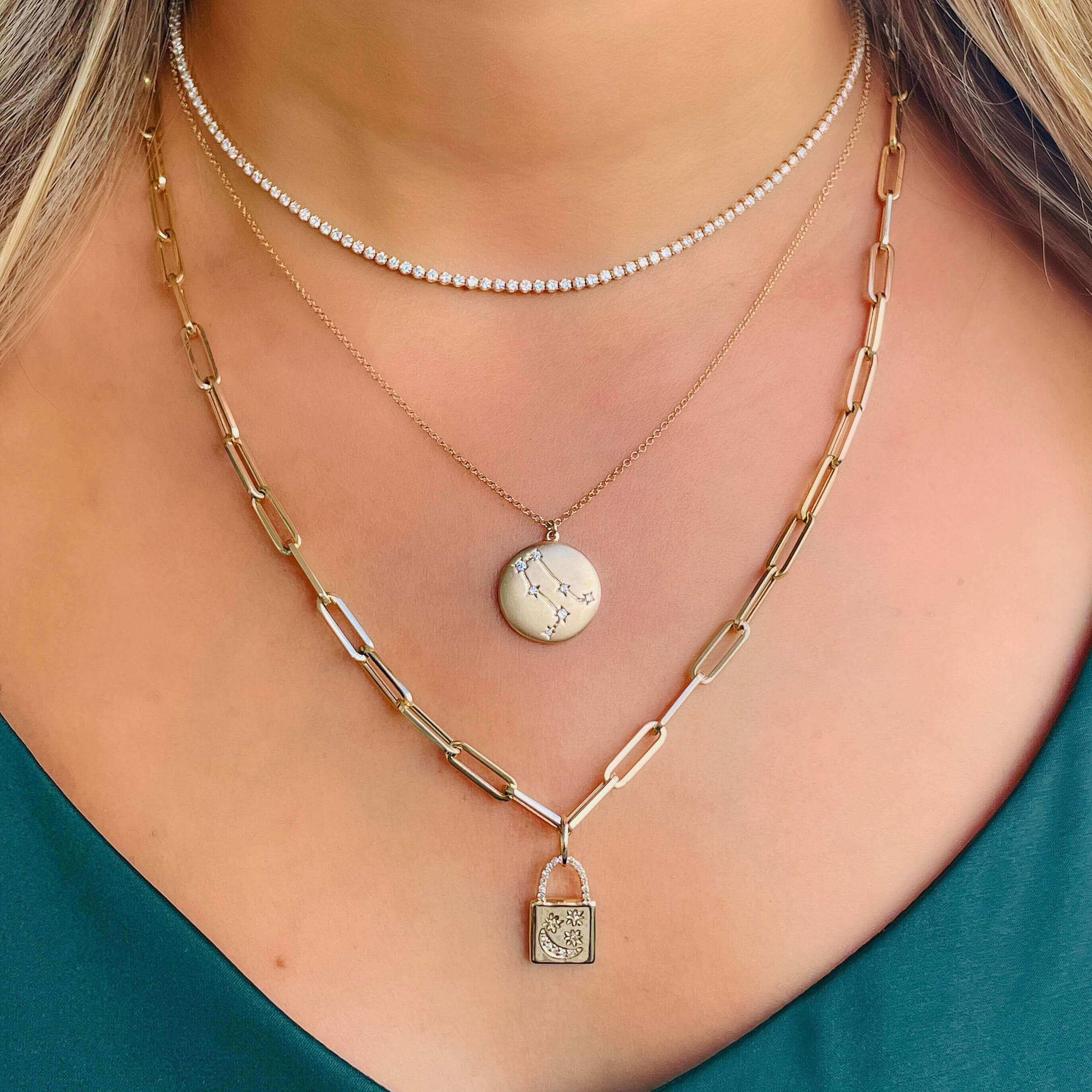 Woman wearing layered necklaces with gold chain lock, marble pendant, and diamond choker, showcasing elegant jewelry collection.