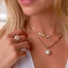 Woman wearing elegant pearl necklace and ring from our luxury jewelry collection.