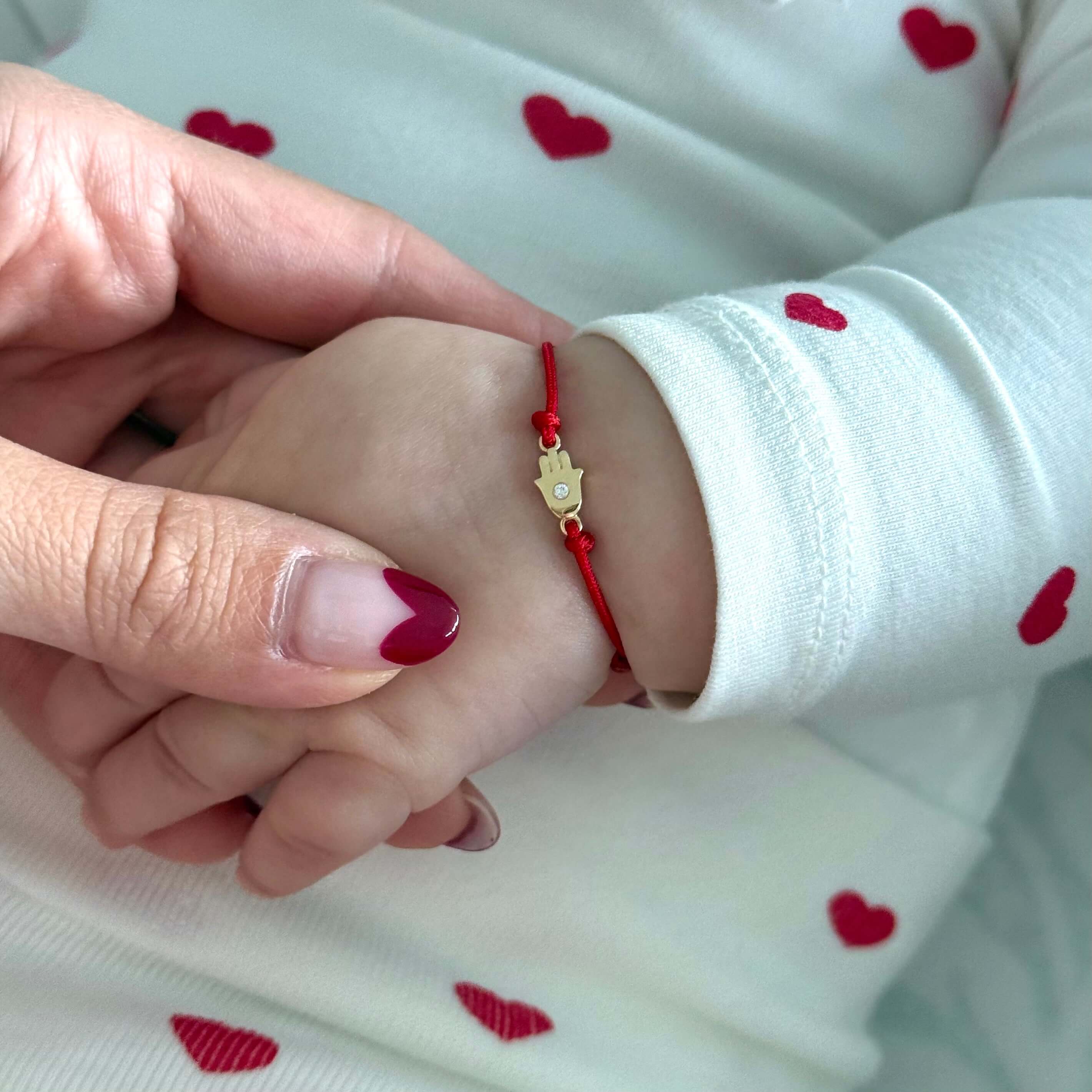 14K gold diamond accented Hamsa cord baby bracelet on a child's wrist, showcasing personalization options and protection.