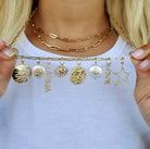 Woman showcasing gold necklace with various unique charms, including star, love, and symbolic designs from our jewelry collection