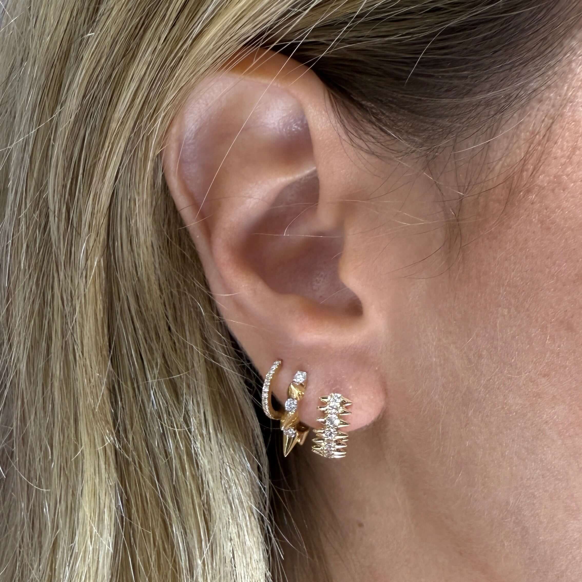 Close-up of an ear wearing gold hoop earrings with a blurred background