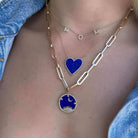 Layered gold necklaces featuring a 'MOM' charm, a blue heart pendant, and a celestial-themed pendant, perfect for a stylish jewelry statement.