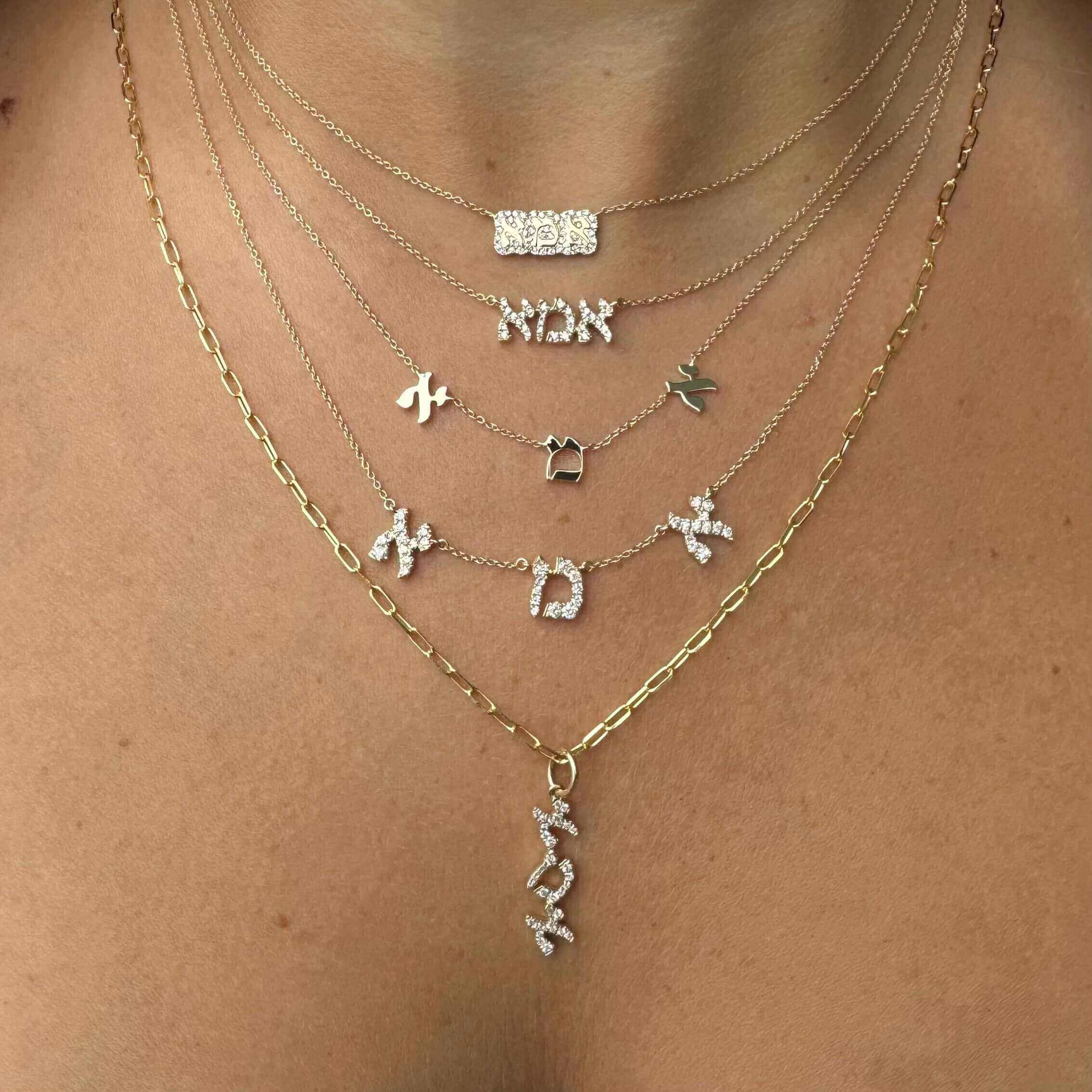 Layered jewelry featuring Hebrew name necklaces in gold and silver tones, perfect for elegant layering.