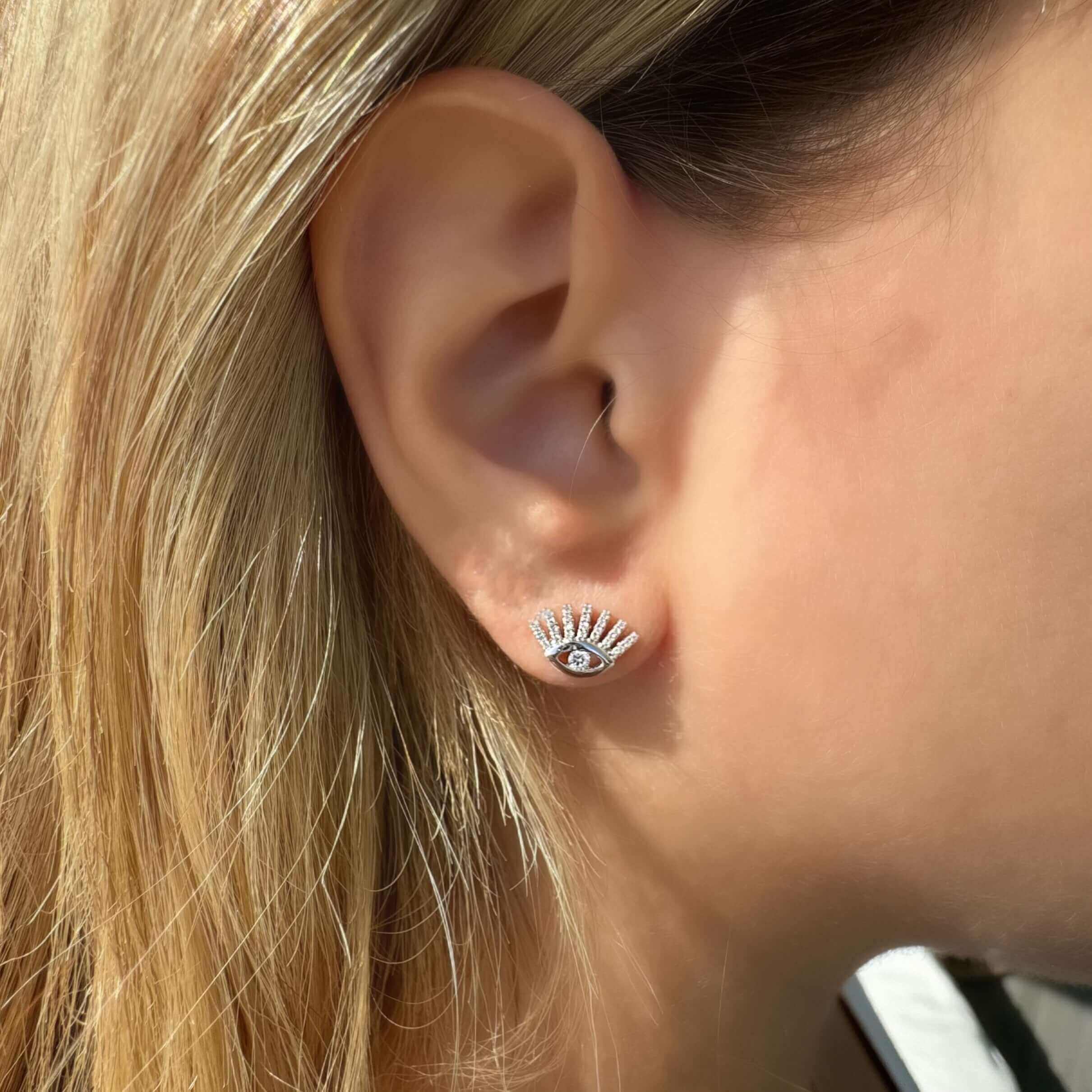 Woman wearing a sparkling eye-shaped earring from our luxury jewelry collection