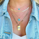 Woman wearing layered gold necklaces with blue accents and various pendant designs from our jewelry collection