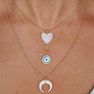 Layered gold necklaces with heart, evil eye, and crescent moon pendants from our jewelry brand.