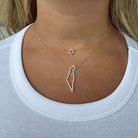 Woman wearing 14K gold necklace with diamond outline of Israel and Star of David charm.