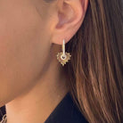 Close-up of a woman's ear wearing a stylish gold heart-shaped earring from our jewelry collection.