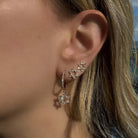 Elegant 14K gold huggie earrings featuring a diamond Star of David design, worn on a model's ear.