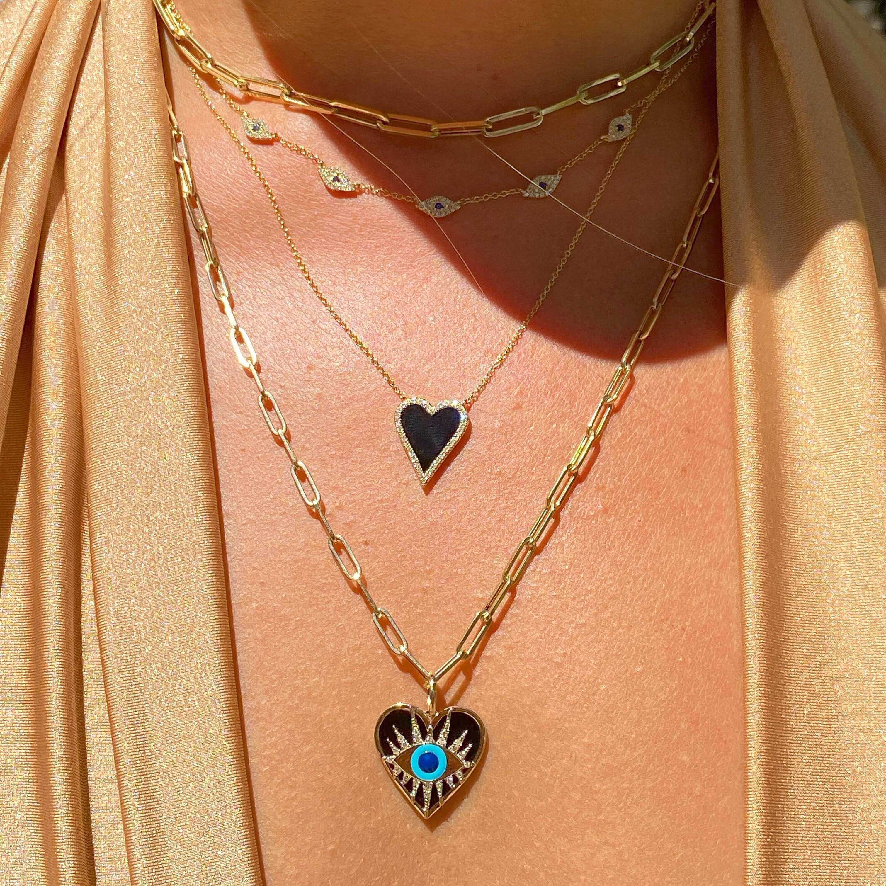 Woman wearing layered gold necklaces with heart pendants from our jewelry brand.