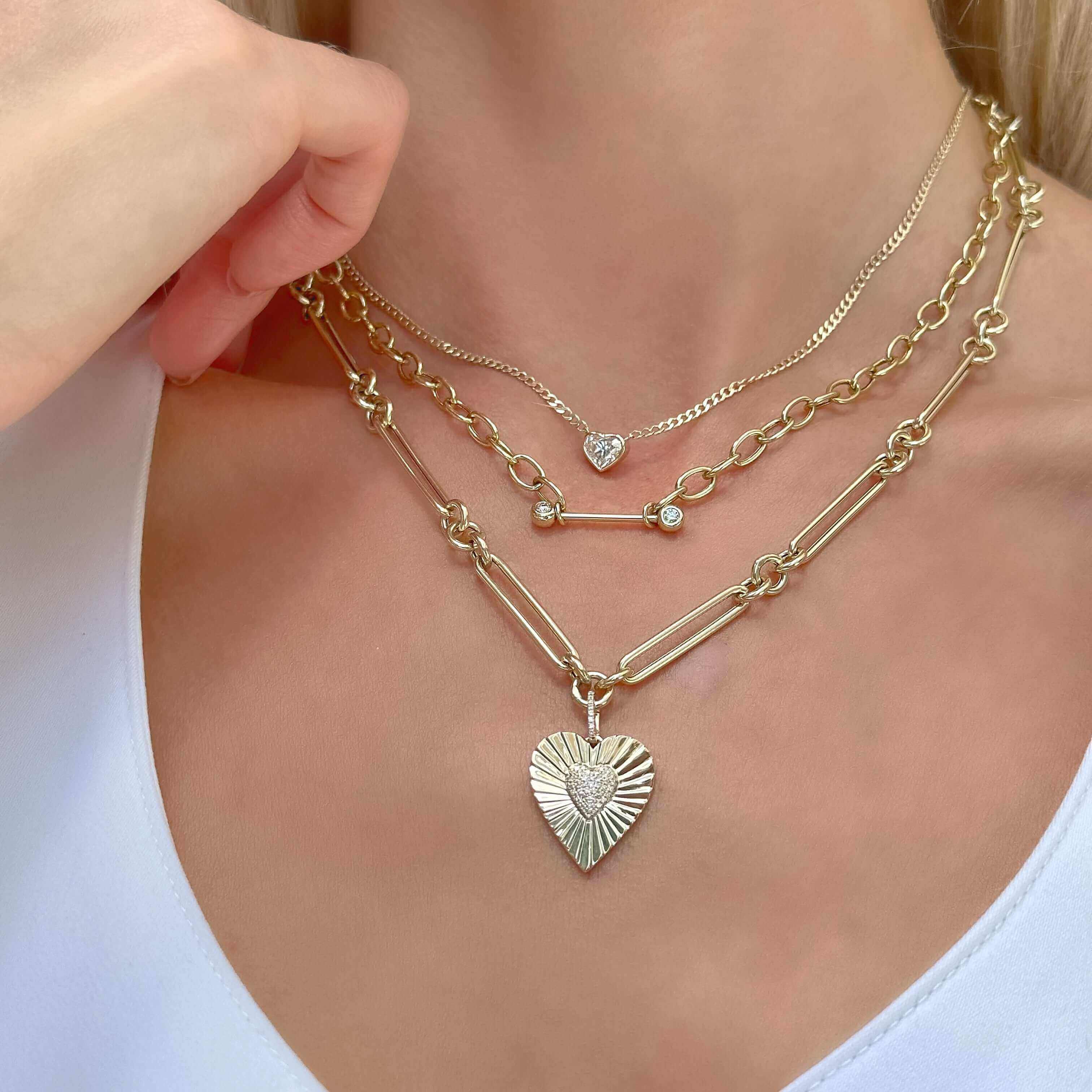 Woman wearing layered gold necklaces with heart-shaped pendant, showcasing elegant jewelry from our brand.