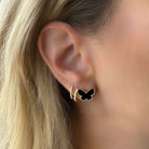 Woman wearing 14K gold onyx butterfly earrings with milgrain detail, highlighting elegant jewelry design.