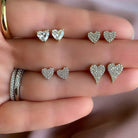 Heart-shaped diamond earrings from our luxury jewelry collection displayed on a hand.