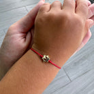 Child wearing 14K Gold Hebrew Initial Cutout Cord Baby Bracelet with red cord, showcasing a star-shaped gold charm.