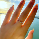 Elegant diamond-studded ring worn on a hand, shown against a serene coastal backdrop, part of our fine jewelry collection.