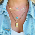 Woman wearing layered gold and blue charm necklaces from our jewelry collection