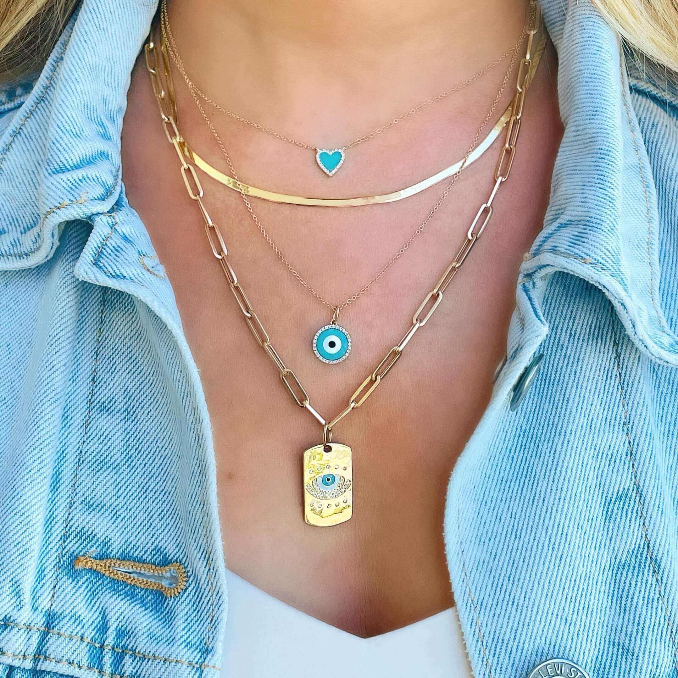 Woman wearing layered gold and blue charm necklaces from our jewelry collection