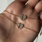 Land Of Israel Cutout Heart Pave Diamond Bracelet © showcased on a hand, featuring two diamond heart charms on a gold chain.