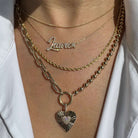 Layered gold necklaces featuring a heart pendant, a nameplate, and a delicate chain for a stylish look.