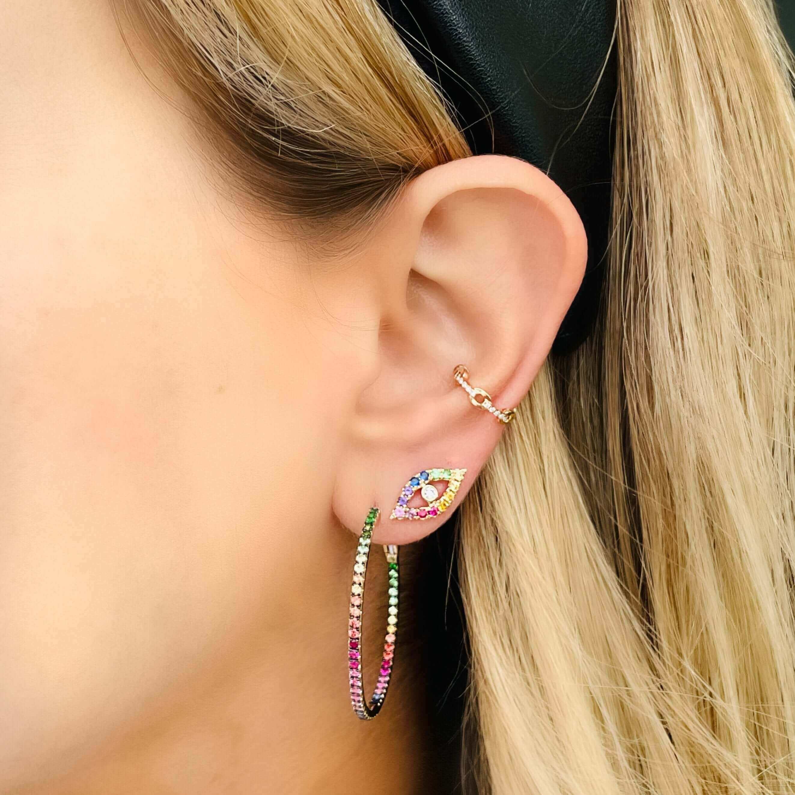 Woman wearing vibrant, multicolored gemstone hoop earring and a stud earring from our jewelry brand.