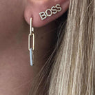 Close-up of ear with gold and silver link earring and "BOSS" crystal stud, jewelry from our elegant collection.