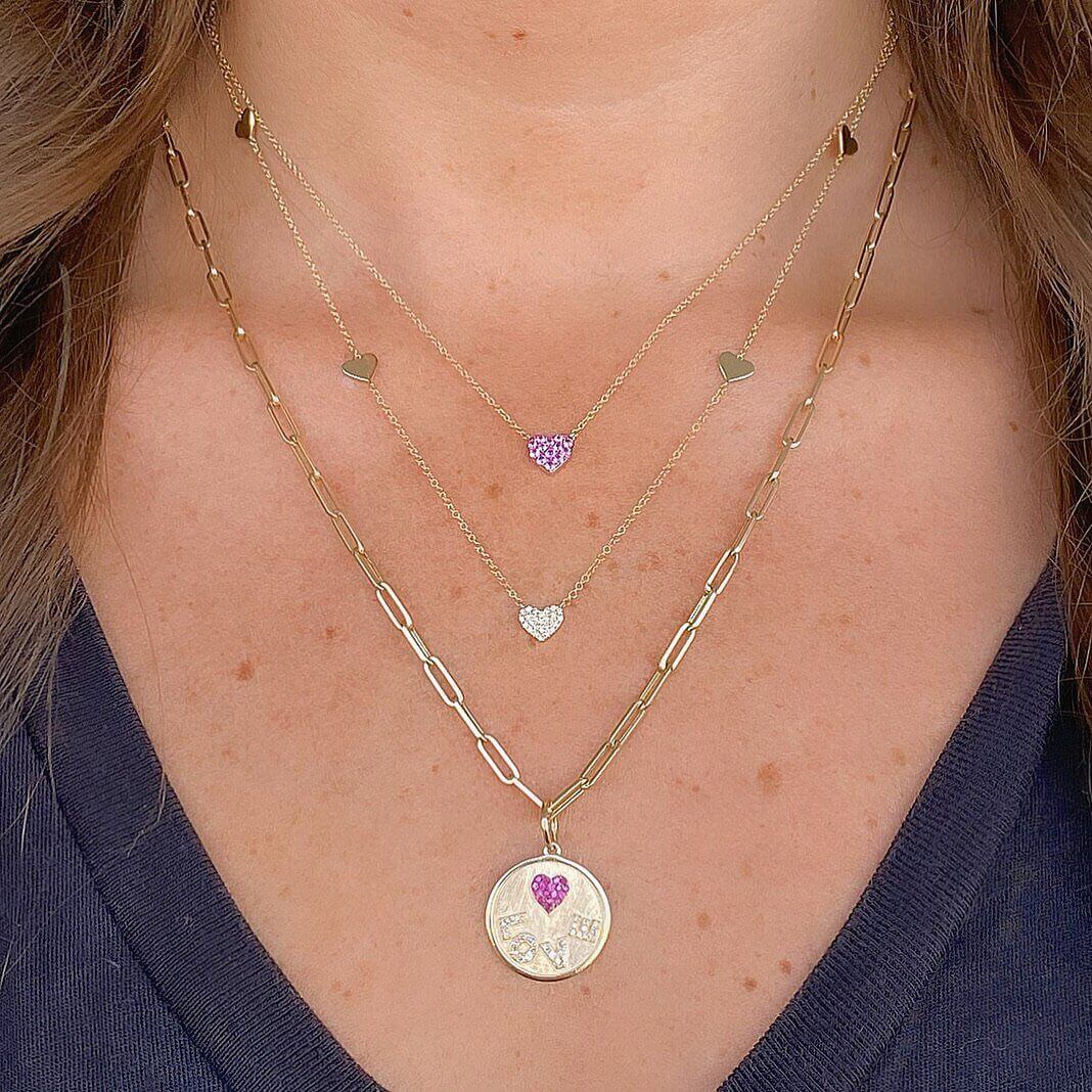 Woman wearing layered gold necklaces with heart pendants from our jewelry brand