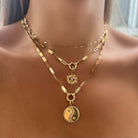 Woman wearing layered gold necklaces with sun and yin yang pendants, from our exclusive jewelry collection