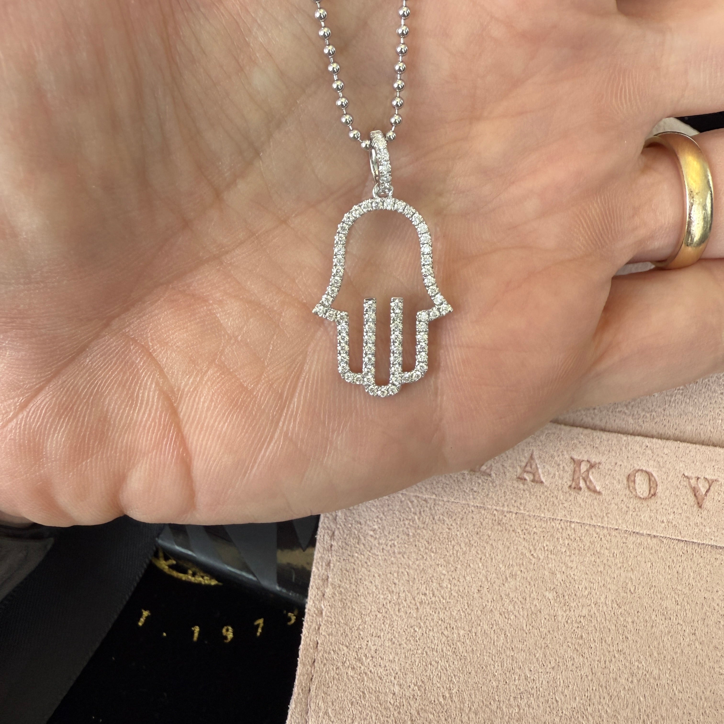 14K gold open diamond hamsa pendant held in hand, showcasing sparkling accents and meaningful design.