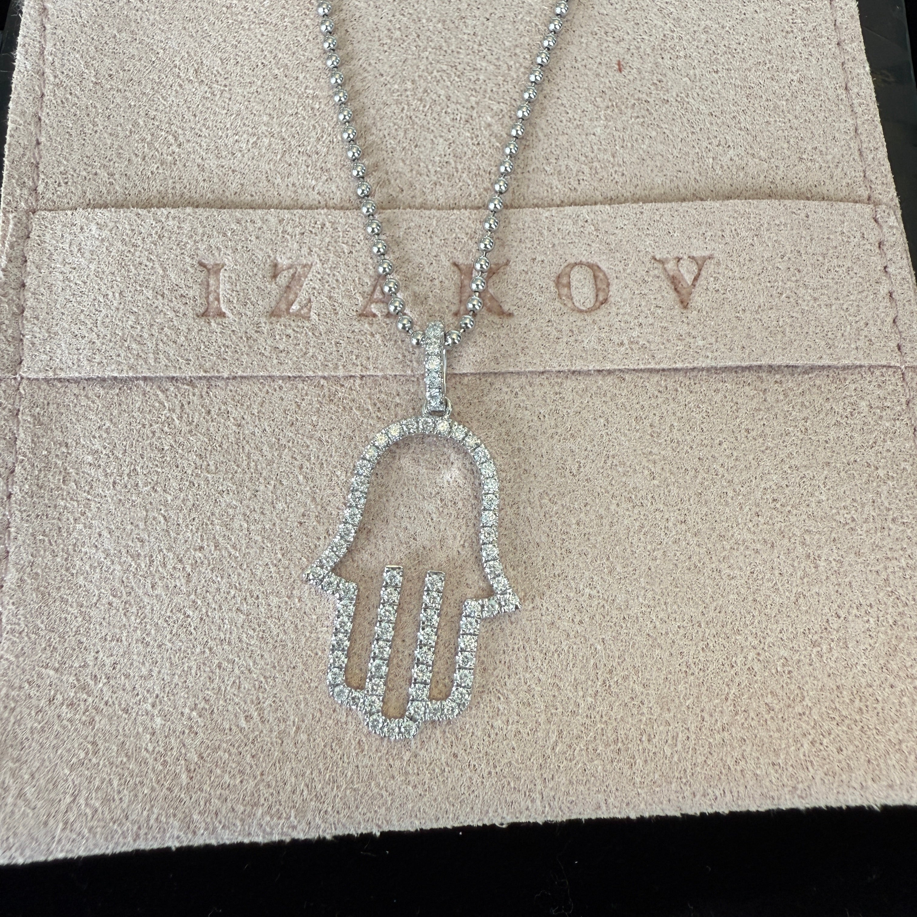 Elegant 14K gold open hamsa pendant with diamond accents on a display pouch, showcasing its spiritual design.